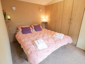 1 dormitorio con cama con sábanas rosas y almohadas moradas en Middlemuir Retreat en Tarbolton