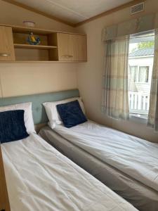 two beds in a small room with a window at Rockley Valley TV36 in Lytchett Minster