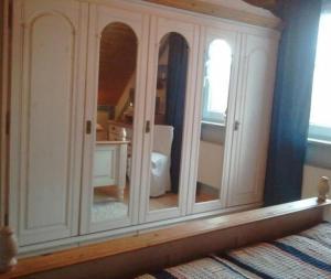 d'une armoire blanche avec des miroirs dans la chambre dans l'établissement Komfortables Ferienhaus in Heidmühle mit Terrasse, Garten und Grill, à Schortens