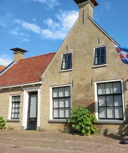 een stenen huis met vier ramen en een dak bij EAstay appartement 2 in Oostermeer