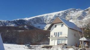 una casa blanca en la nieve con montañas en el fondo en Rooms Savin kuk view, en Žabljak