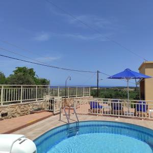 a swimming pool with chairs and an umbrella at Helidonia Villas in Pigi