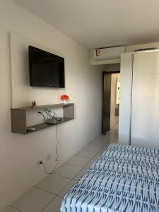 um quarto com uma cama e uma televisão na parede em Flat 1218, no residencial monte castelo em Bezerros