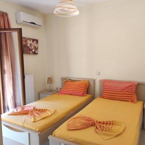 two beds in a room with orange and orange pillows at Helidonia Villas in Pigi
