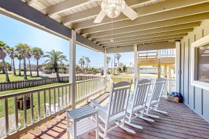a porch with four chairs and a ceiling fan at Old Town Treasure in Port Aransas