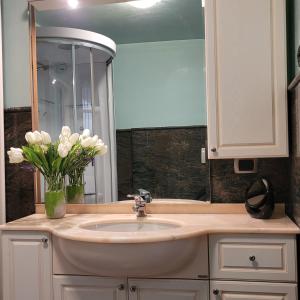 une salle de bain avec un lavabo et un vase de fleurs blanches dans l'établissement Il Cortiletto Mountain Lake Iseo Hospitality, à Costa Volpino