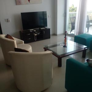 sala de estar con sillas, TV y mesa de centro en Apartamento Cartagena, en Cartagena de Indias