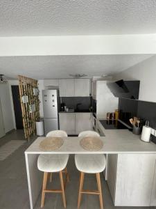een keuken met 2 stoelen en een tafel met een aanrecht bij Atmosphère Cosy de 50m2 in Castelnau-le-Lez