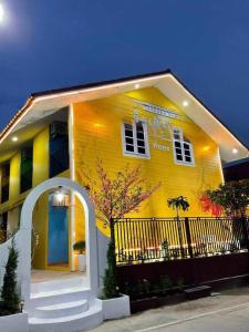 una casa amarilla con una valla negra delante de ella en ลิตเติ้ลโฮม ที่พักเพชรบุรี en Phetchaburi