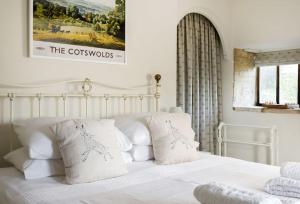 um quarto com uma cama branca e almofadas brancas em Slatters Cottage - 17th Century Cotswolds Cottage em Bourton on the Hill