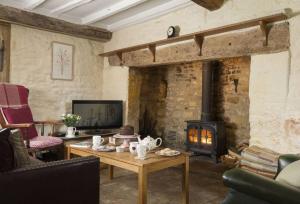 a living room with a fireplace and a table at Slatters Cottage - 17th Century Cotswolds Cottage in Bourton on the Hill