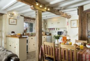 a kitchen with white cabinets and a table with chairs at Slatters Cottage - 17th Century Cotswolds Cottage in Bourton on the Hill