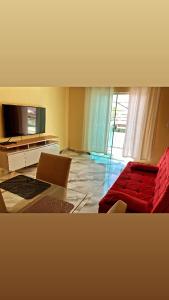 ein Wohnzimmer mit einem roten Sofa und einem TV in der Unterkunft Dunas Apartamento in Cabo Frio