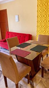 einen Tisch mit Stühlen und eine rote Couch in einem Zimmer in der Unterkunft Dunas Apartamento in Cabo Frio