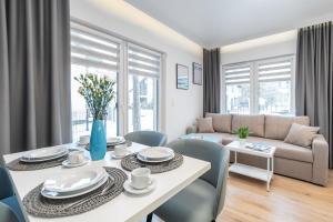 sala de estar con mesa, sillas y sofá en Dziwnówek Apartament Horizon Park 4A en Dziwnówek