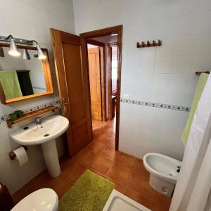 un bagno con lavandino, WC e specchio di Casa adosada en Urbasur ISLANTILLA a Islantilla