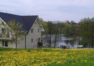 a house in a field of flowers next to a lake at Kaszubskie Nuty in Miechucino
