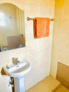 bagno con lavandino bianco e specchio di Miraph Apartment ad Abuja