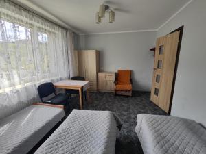 a bedroom with two beds and a desk and a table at Agroturystyka Elżbieta i Juliusz in Muszyna