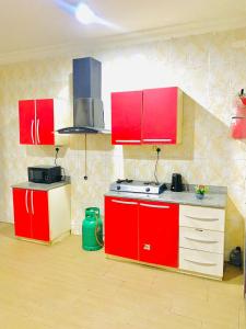 una cucina con armadi rossi e piano cottura di Miraph Apartment ad Abuja
