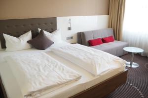 a bedroom with a large white bed with red pillows at Hotel Fuchsen in Kirchheim unter Teck