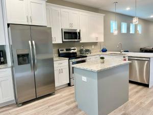 a kitchen with stainless steel appliances and white cabinets at The Billiard close to downtown with fenced yard in Sanford