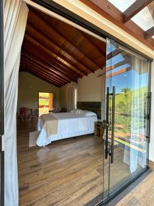 a bedroom with a bed and a sliding glass door at Hotel Fazenda Palmeiras in Rio Casca