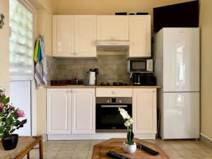 une cuisine avec des armoires blanches, un réfrigérateur et une table dans l'établissement Loc. Ste-Anne, maisonnette plein-pieds 2 à 4 pers., à Sainte-Anne