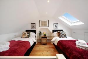 two beds in a room with a skylight at Harry Potter Experience - 3 Bed House In Watford in Watford