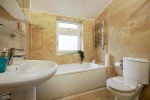 a bathroom with a tub and a toilet and a sink at Harry Potter Experience - 3 Bed House In Watford in Watford