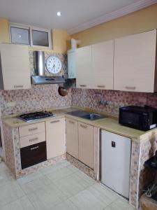 a kitchen with white cabinets and a clock on the wall at Nour in Sousse