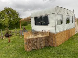 a white trailer parked in a field with a grill at Caravane à la nuitée in Saint-Parize-le-Châtel