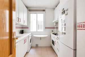 een keuken met witte kasten, een wastafel en een raam bij Serrano & Claudio Coello: Lujo, Luz y Elegancia in Madrid