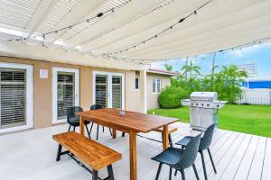 a patio with a wooden table and chairs and a grill at Walk to Beach Luxury 5BR & 3BA Villa Hollywood Lakes in Hollywood