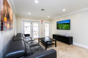 a living room with a leather couch and a table at Walk to Beach Luxury 5BR & 3BA Villa Hollywood Lakes in Hollywood +27 photos