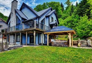 a large blue house with a porch and a deck at Chalet 19 Chemin Blanc by Les Chalets Alpins in Stoneham