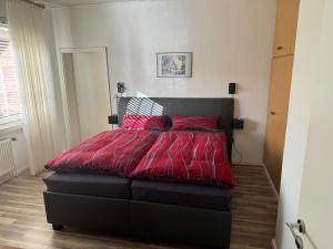 ein Schlafzimmer mit einem großen roten Bett mit roten Kissen in der Unterkunft Schwalbenhof in Westerstede
