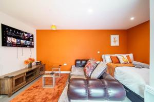 - une chambre avec des murs orange, un canapé et un lit dans l'établissement New corner studio apartment in Sheffield, à Sheffield