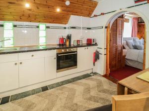 uma cozinha com armários brancos, uma mesa e um sofá em The Nook em Llanrwst