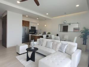a living room with a white couch and a kitchen at Luxury Beachfront Condo in Rosarito with Pool & Jacuzzi in Rosarito