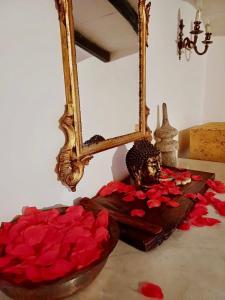a mirror and a bowl of red roses on a table at Borgo Vecchio in Carbognano