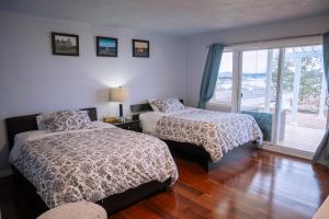 a bedroom with two beds and a balcony at HOV B&B House -Hospitality Ocean View Victoria- in Victoria