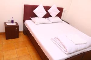 um quarto com uma cama com lençóis brancos e almofadas em Hotel Ashirwad em Jabalpur