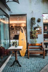 a surfboard leaning against a wall with a table and a bench at Casanova Residence in Rio de Janeiro