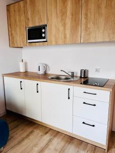 cocina blanca con fregadero y microondas en Apartamenty na Nadmorskiej, en Władysławowo