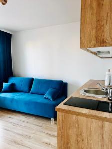 Sofá azul en la sala de estar con lavamanos en Apartamenty na Nadmorskiej, en Władysławowo