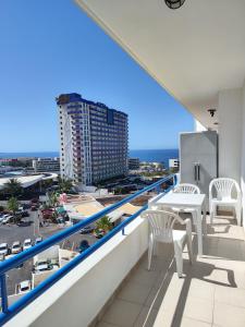 un balcone con sedie bianche, tavolo e un edificio di Olga Paraiso del Sur a Playa Paraiso
