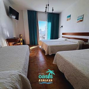 コニル・デ・ラ・フロンテーラにあるHotel Oasis Atalayaのベッド3台と窓が備わるホテルルームです。