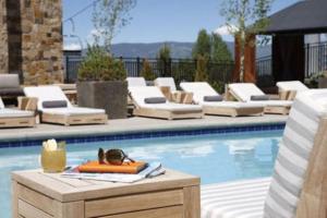 a pool with lounge chairs and a table with a drink and sunglasses at Snowmass Viceroy 1 Bedroom Residence in Snowmass Village