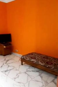 Jijel location F3 avec piscine plein air في جيجل: سرير في غرفة بجدار برتقالي